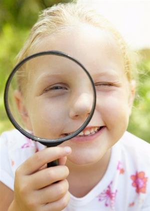 child looking through a magnifying glass 